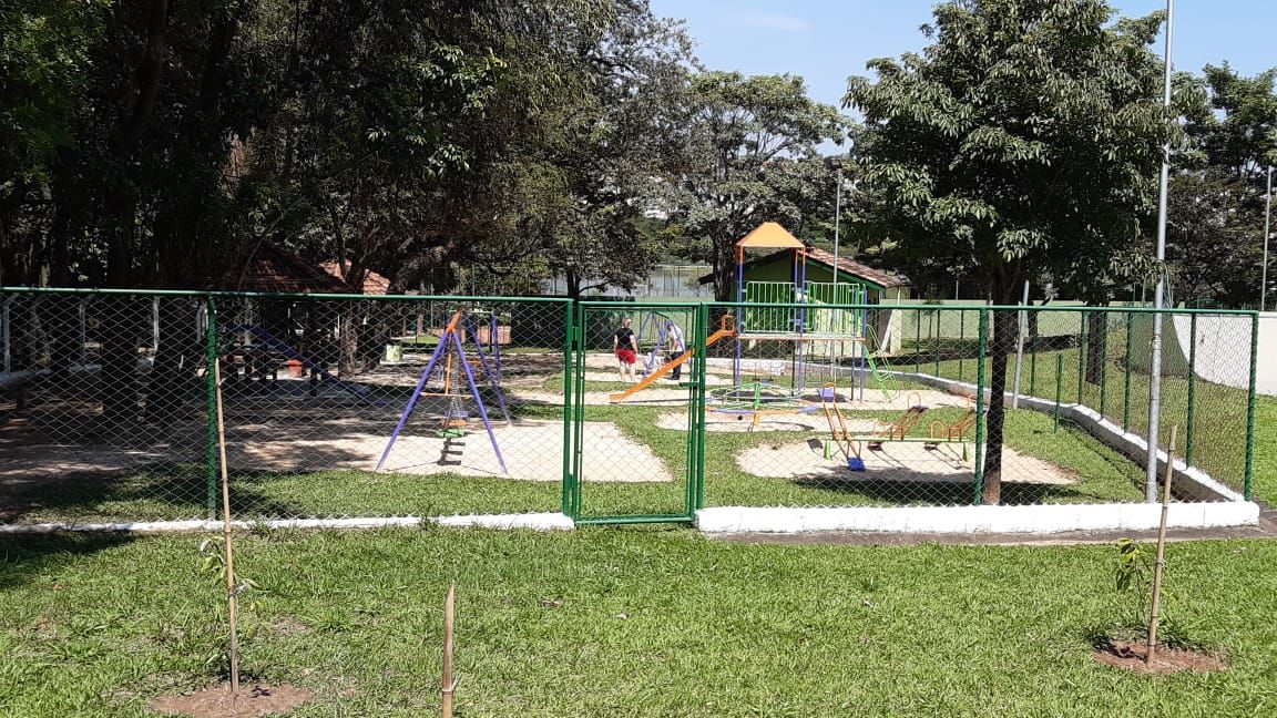 Playground com balanços em área gramada e arborizada